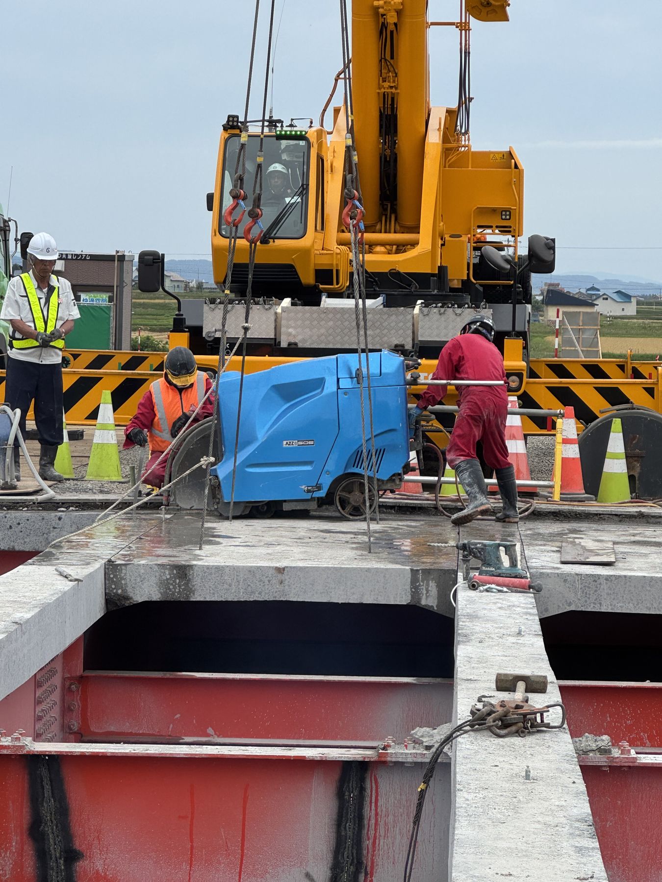 クレーンと連携して橋梁の床版を切断する作業チーム